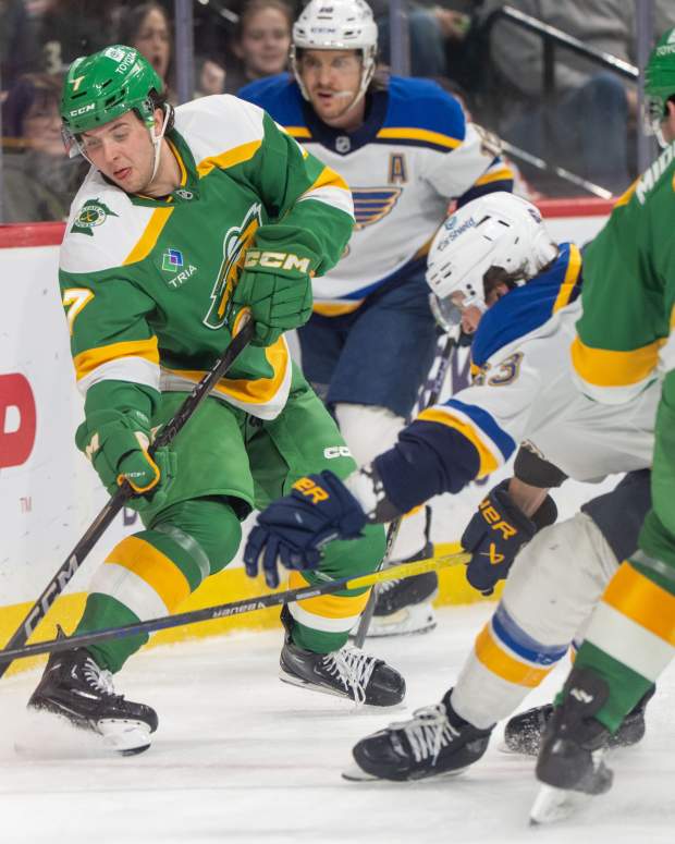 Mar 15, 2025; Saint Paul, Minnesota, USA; Minnesota Wild defenseman Brock Faber (7) clears the puck away from St. Louis Blues left wing Jake Neighbours (63) behind the Minnesota Wild net in the third period at Xcel Energy Center.