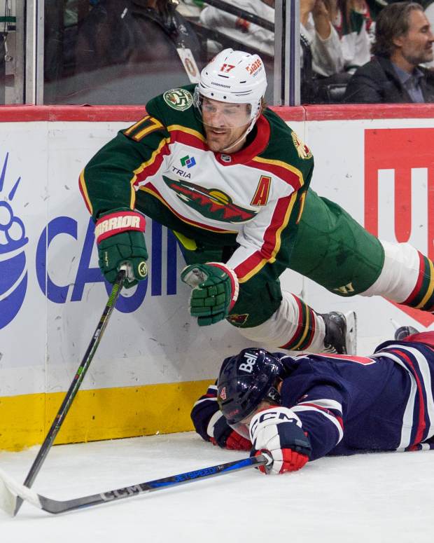 Oct 28, 2025; Saint Paul, Minnesota, USA; Minnesota Wild left wing Marcus Foligno (17) is tripped by Winnipeg Jets defenseman Neal Pionk (4) in the second period at Grand Casino Arena. Mandatory Credit: Matt Blewett-Imagn Images