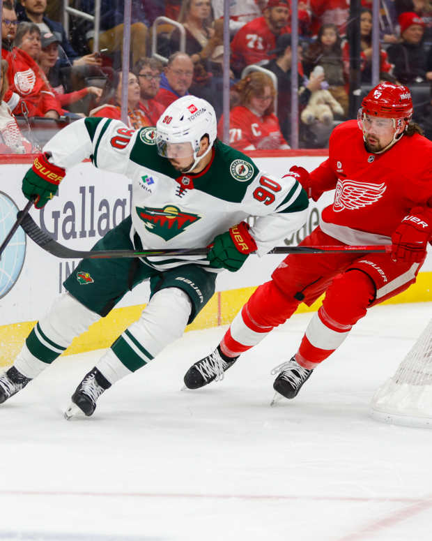 Feb 22, 2025; Detroit, Michigan, USA; Minnesota Wild center Marcus Johansson (90) handles the puck against Detroit Red Wings defenseman Justin Holl (3) during the first period at Little Caesars Arena. Mandatory Credit: Brian Bradshaw Sevald-Imagn Images  