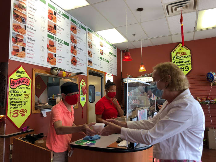 Kevan Tran hands food to a customer as his niece, Jackie Quach, works at the register.