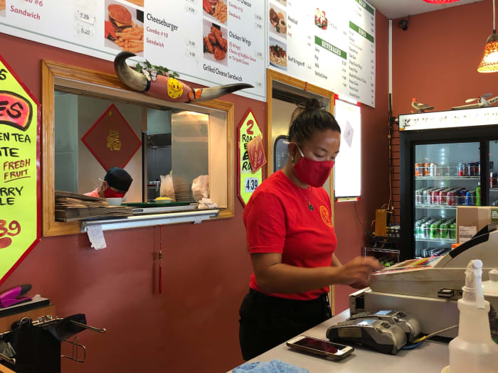 Jackie Quach works the front counter as her uncle, Kevan Tran, prepares food behind her in the kitchen.