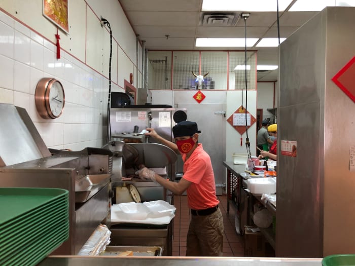 Tran turns to smile at the camera as he slices the roast beef.