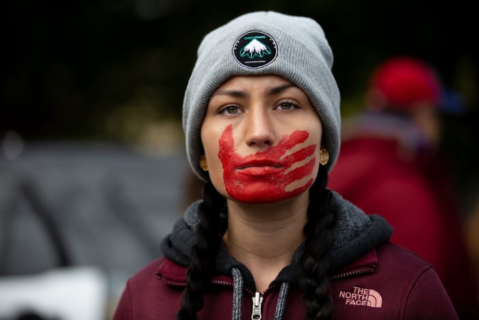 A participant in the Greater Than Fear rally in Rochester. A red hand across the mouth has become a symbolic representation of violence that affects Indigenous women.